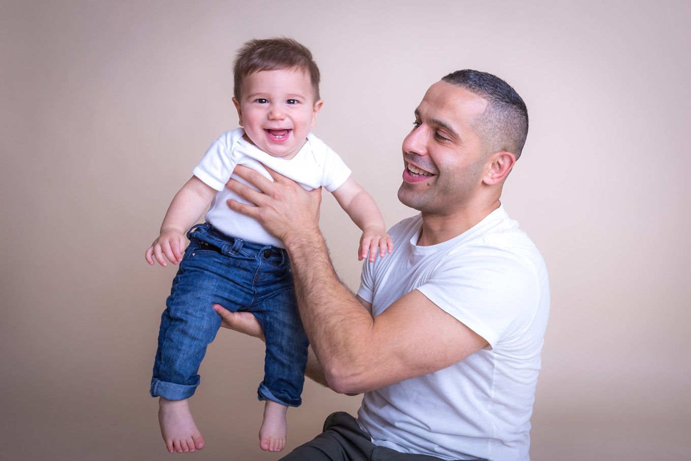Portrait of a baby boy and his dad in a studio with backdrop and lighting equipment